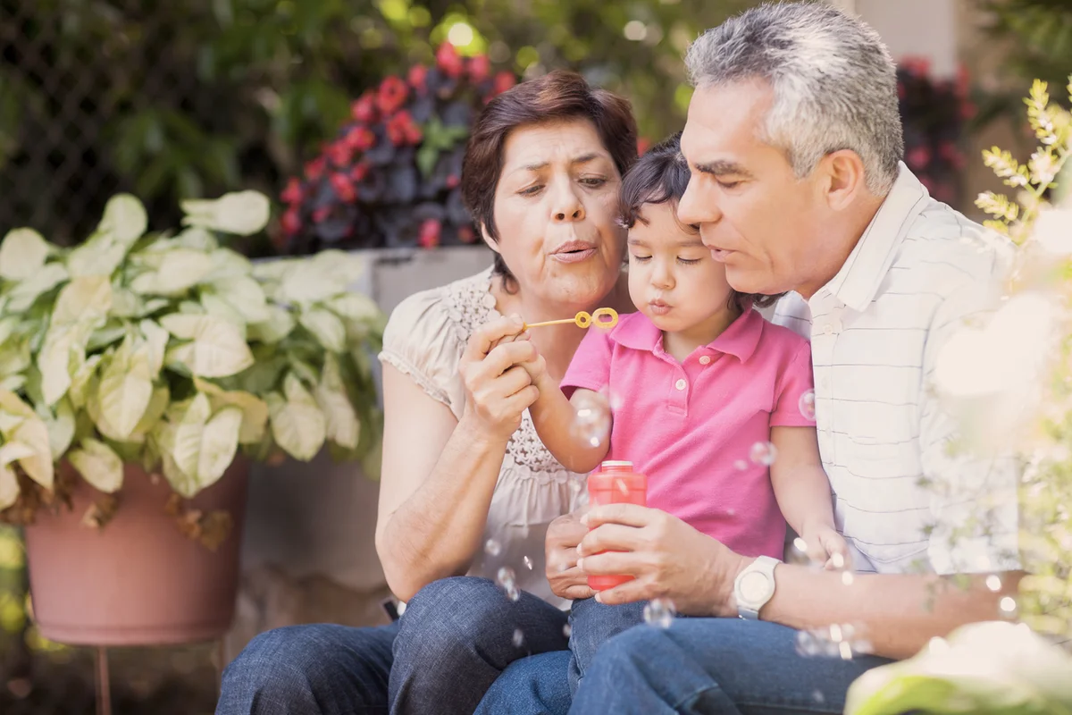 Grandparents and granddaughter making bubbles