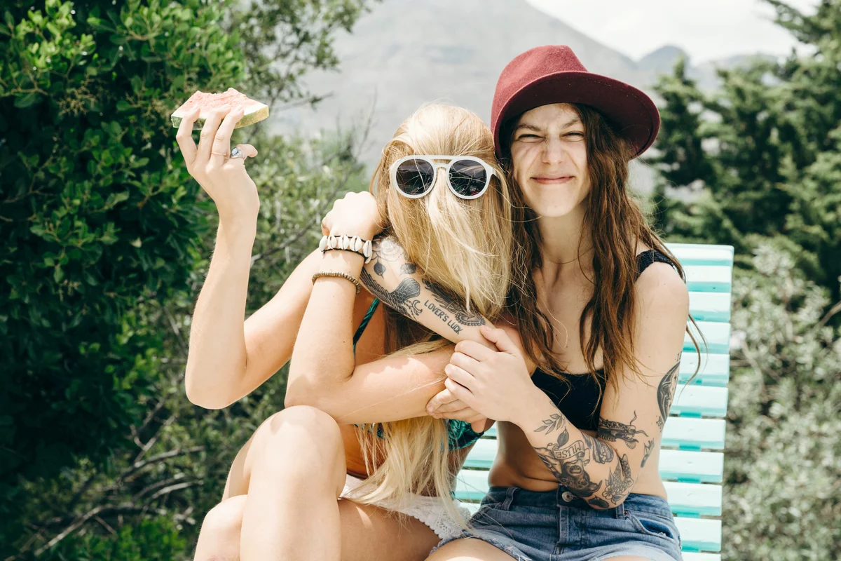 Happy oddball girlfriends embrace outdoors with watermelon in hand