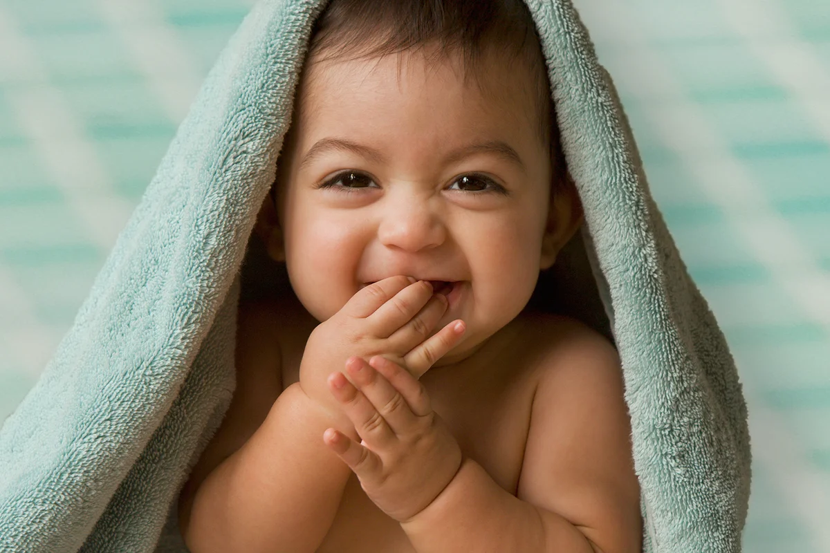 baby sitting under towel