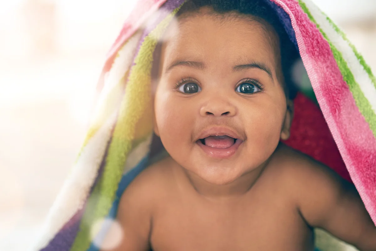 adorable baby covered in a colorful blanket at home