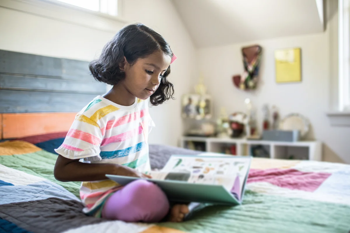 Girl reading book on her bed