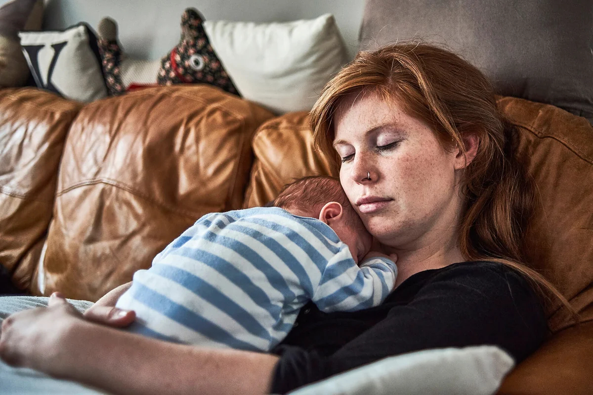 A mother and new born baby taking a nap together