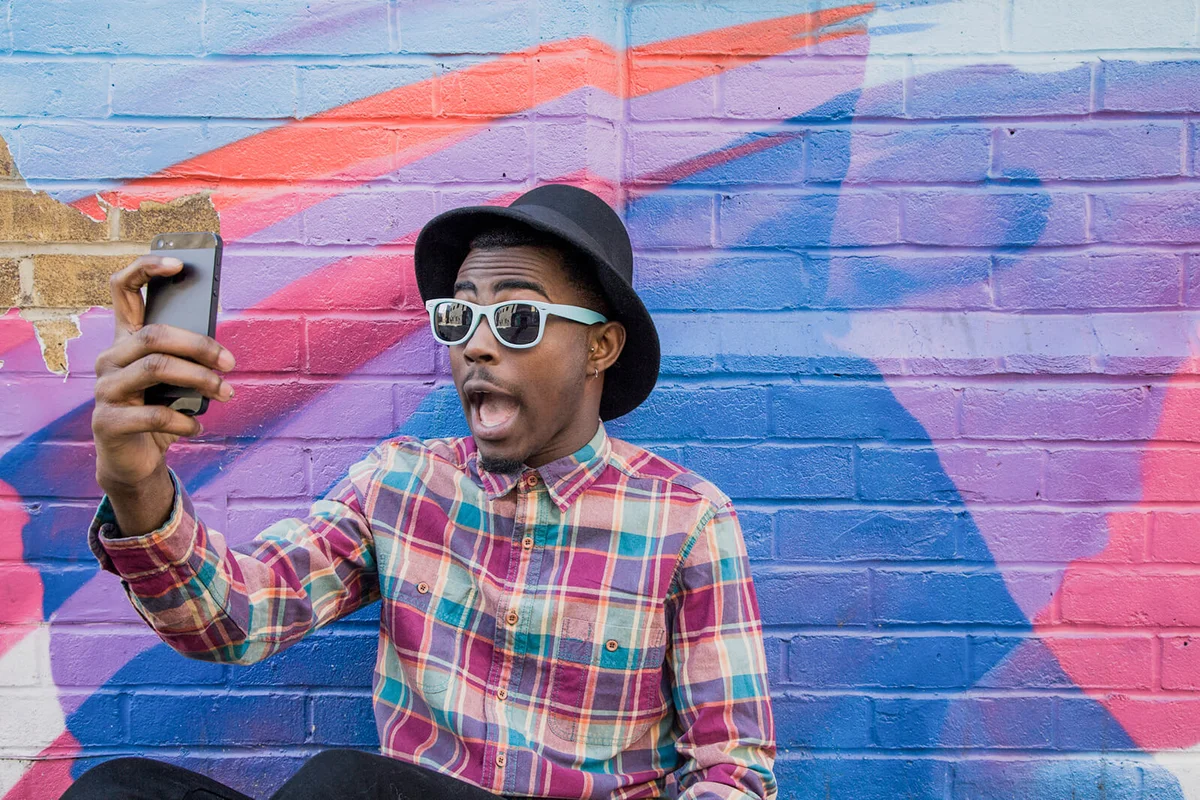 man taking selfie near colorful wall