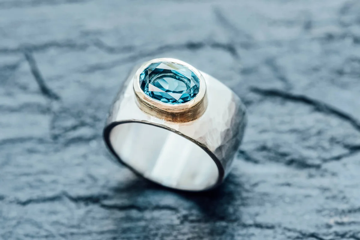 Silver ring with Topaz in gold setting on slate