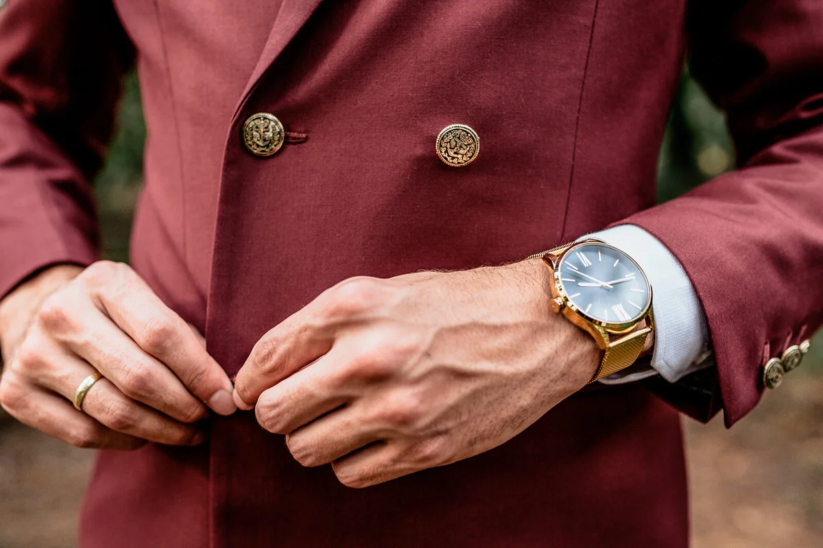man wearing a suit and golden watch buttoning his jacket