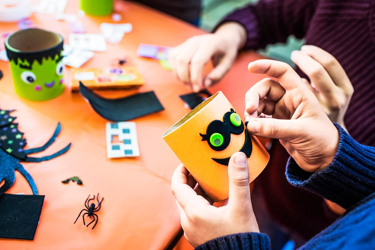 boy making smiley face decoration at table during Halloween party