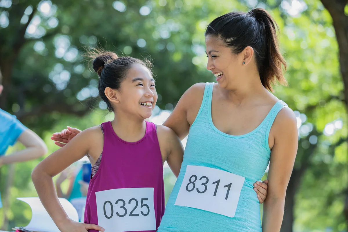 mother and daughter pose together during a marathon