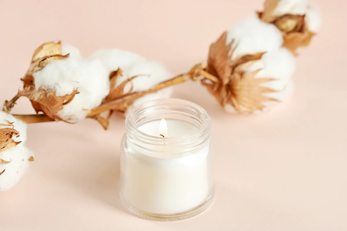 A cotton flower and a white candle in a glass jar