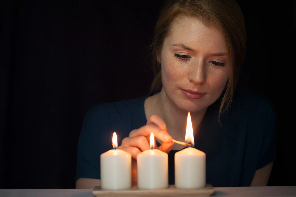 Portrait of young woman lighting candles