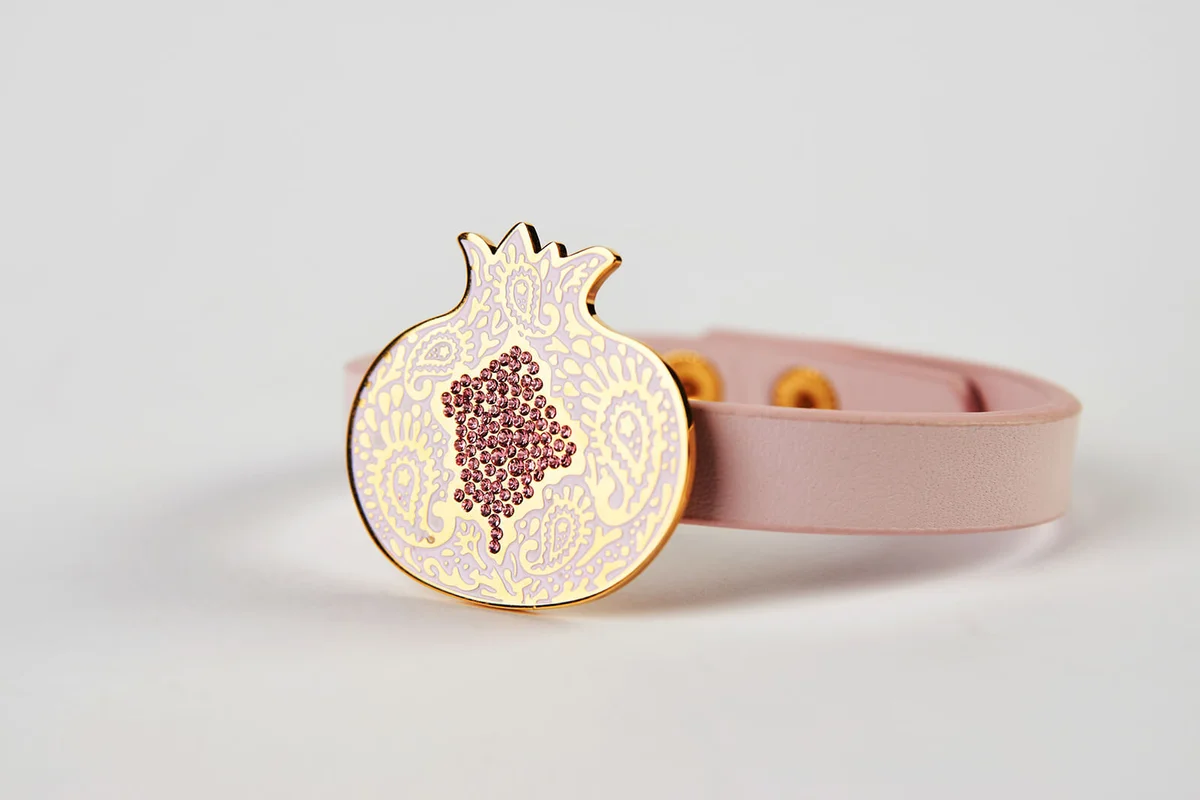 Pink leather and gold cuff bracelet on white background with copy space