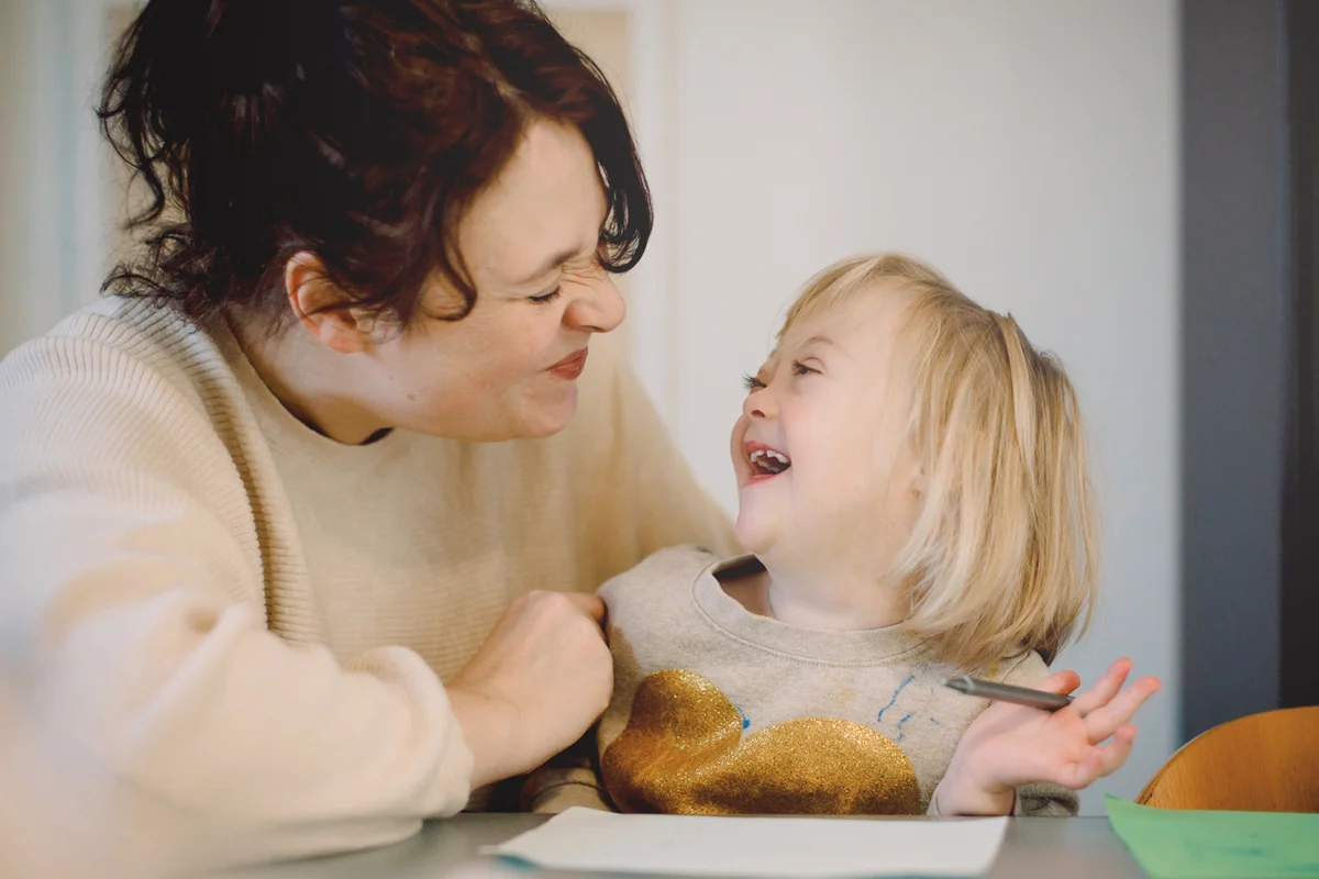 Mother making facial expressions while playing with  daughter