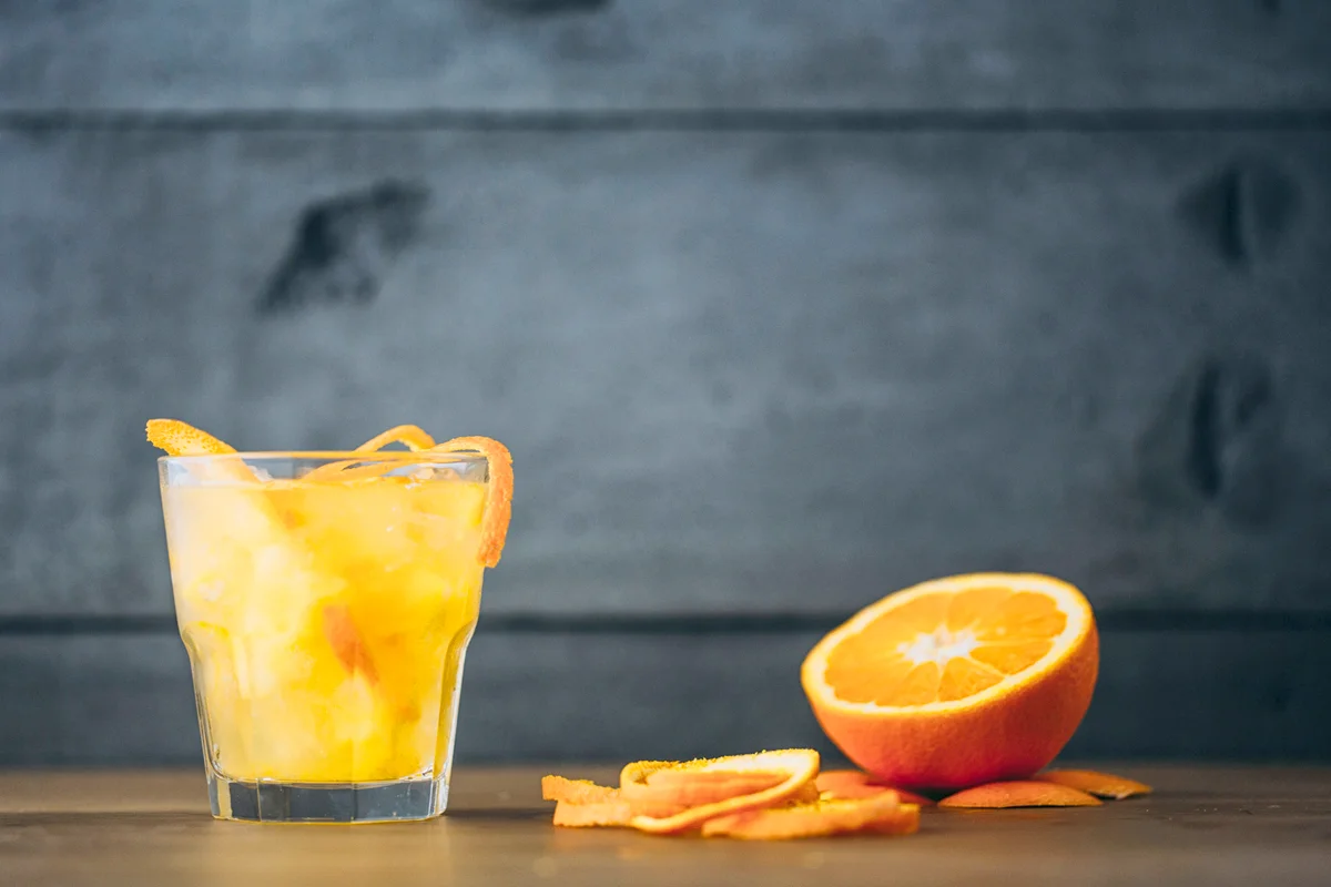 Vodka and orange juice with peel and sliced fruit