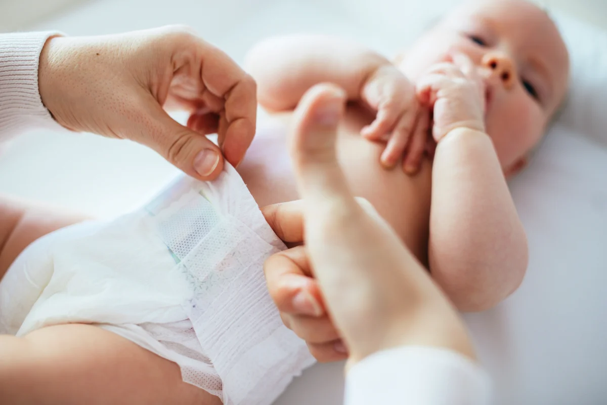 Mother testing if diaper is too tight after changing