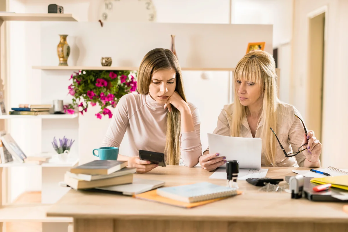 Worried mother and daughter calculating financial reports together