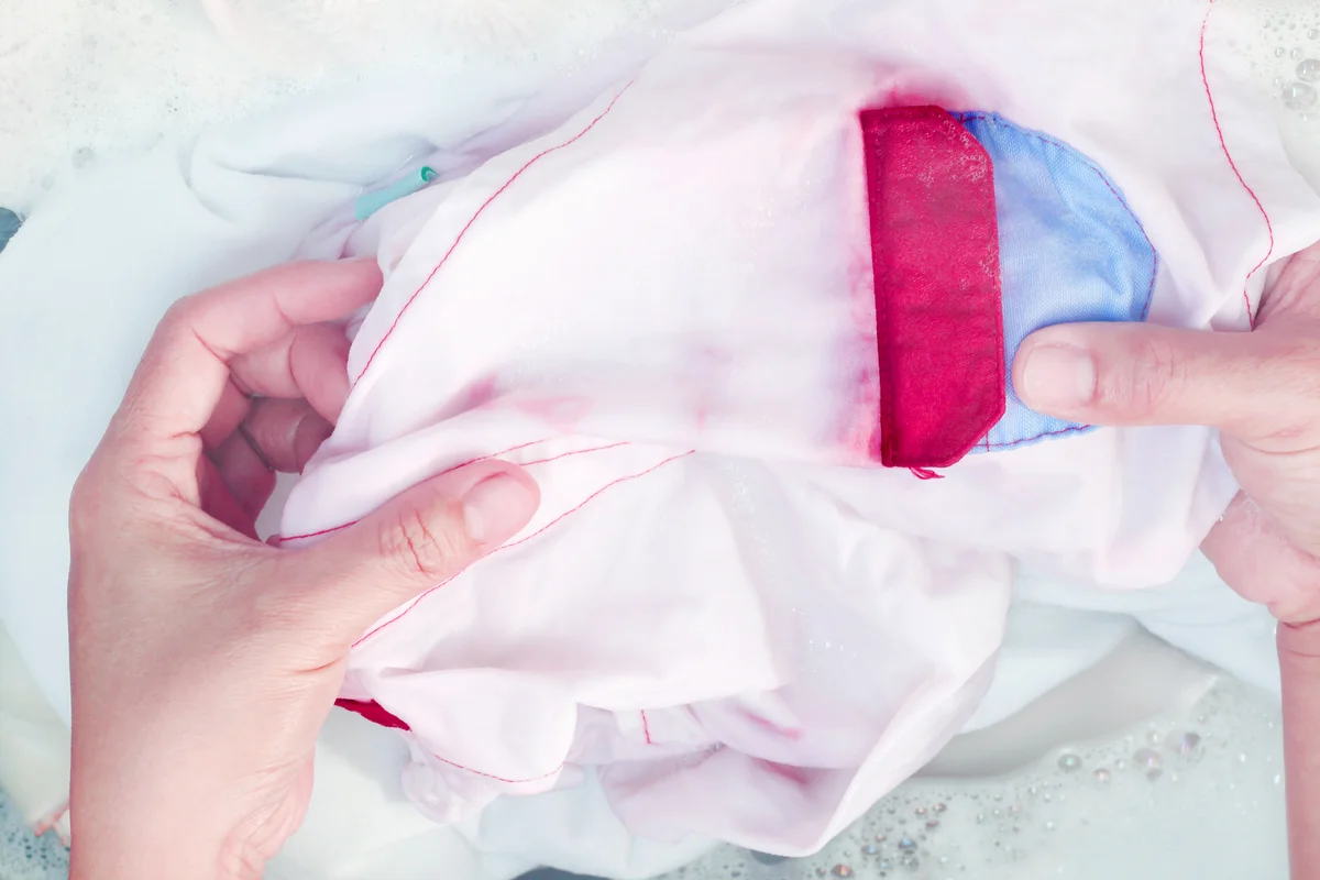 Woman's hands washing white clothes mess up red color in the basin