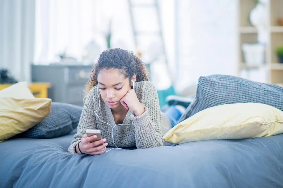 A teenage girl listening to music indoors in her bedroom