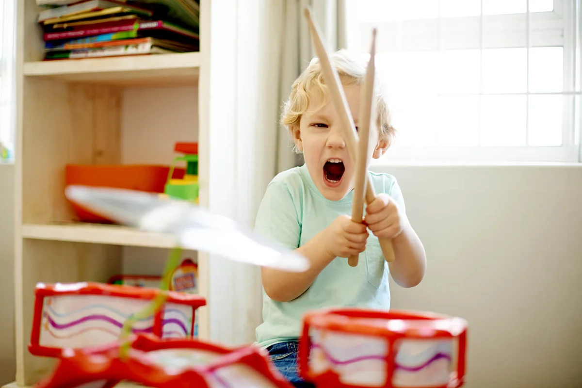 little boy playing with a toy drum