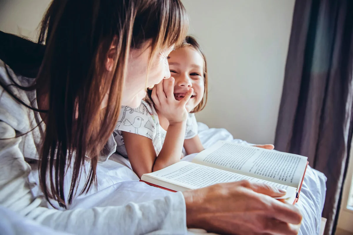 Mother and daughter reading book in bed