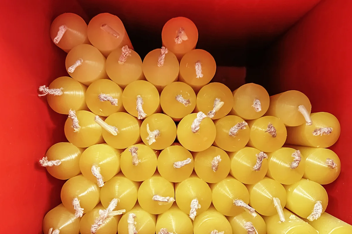 Group of yellow candles with white wicks placed in a red square box