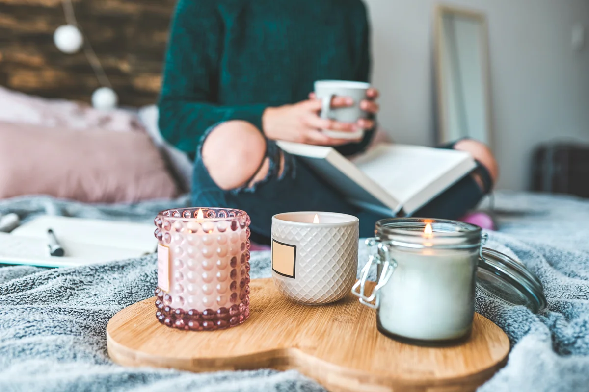 Woman relaxing with a book and a cup of coffee and scented candles
