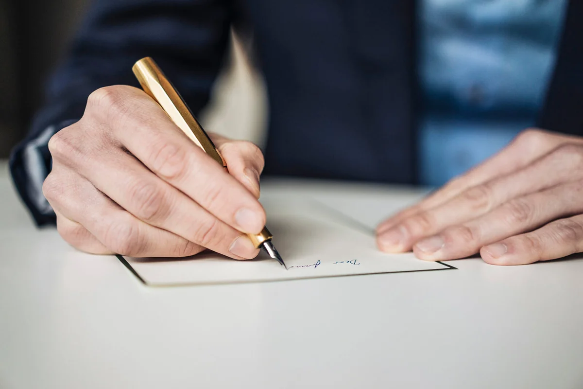 Hand of businessman writing with golden fountain pen