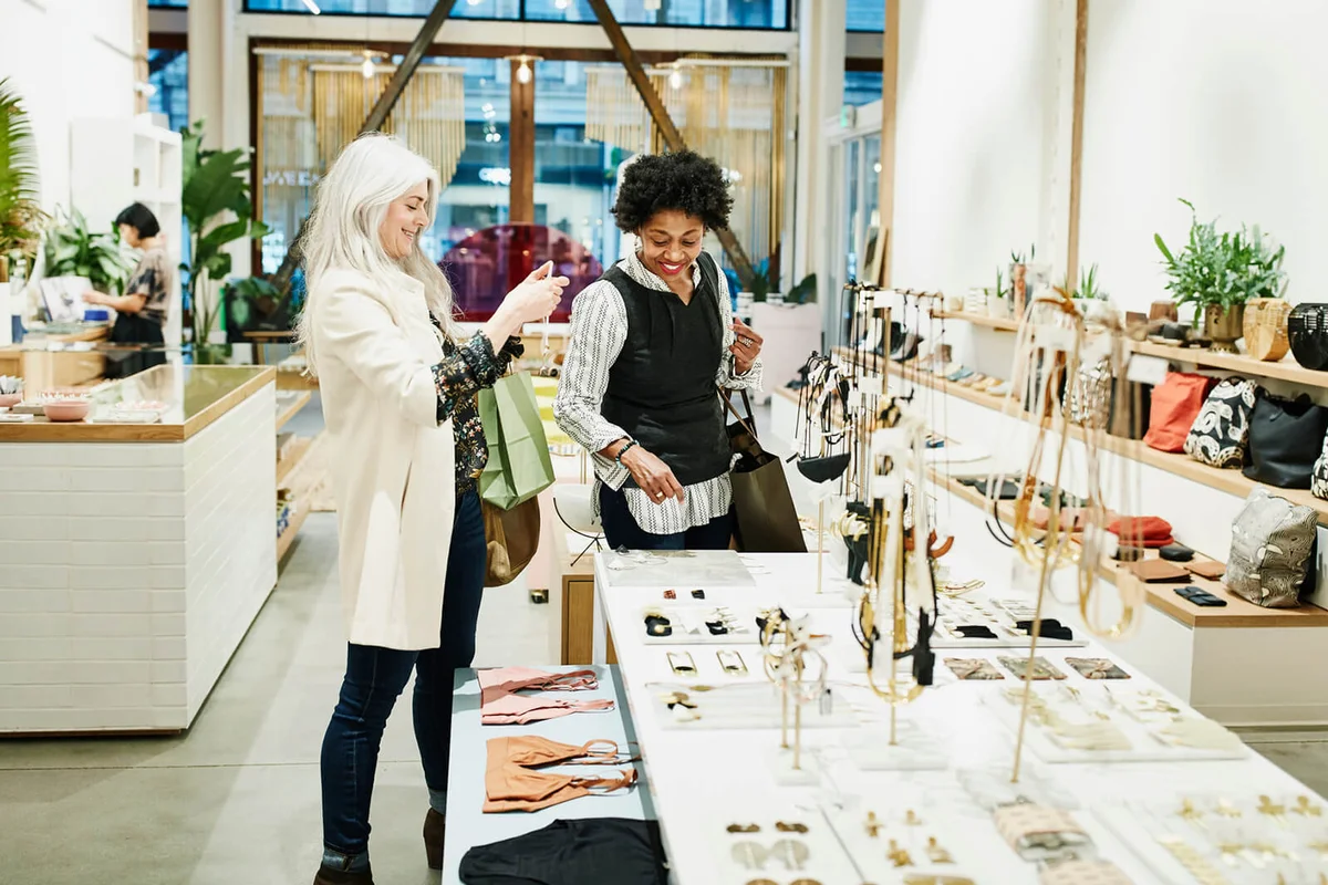 Smiling mature female friends admiring jewelry while shopping together