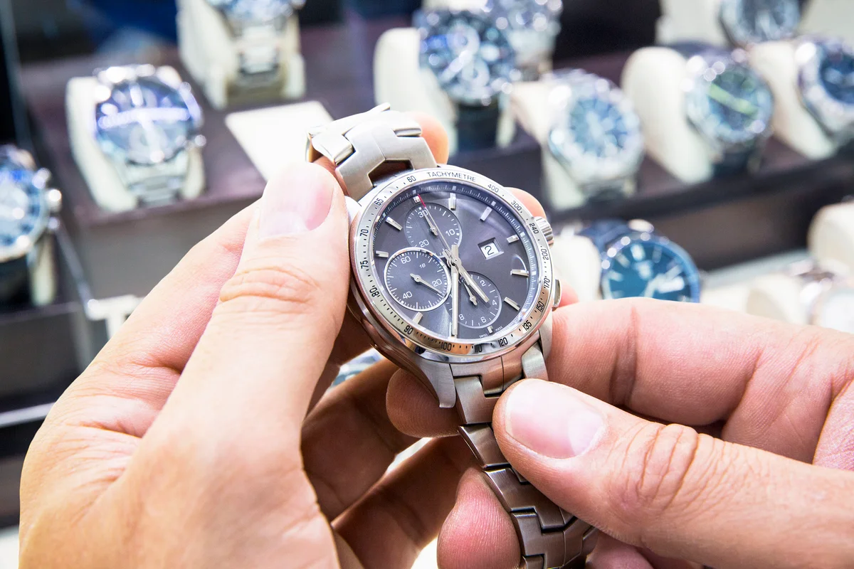 Mens wristwatch being held in a watch shop