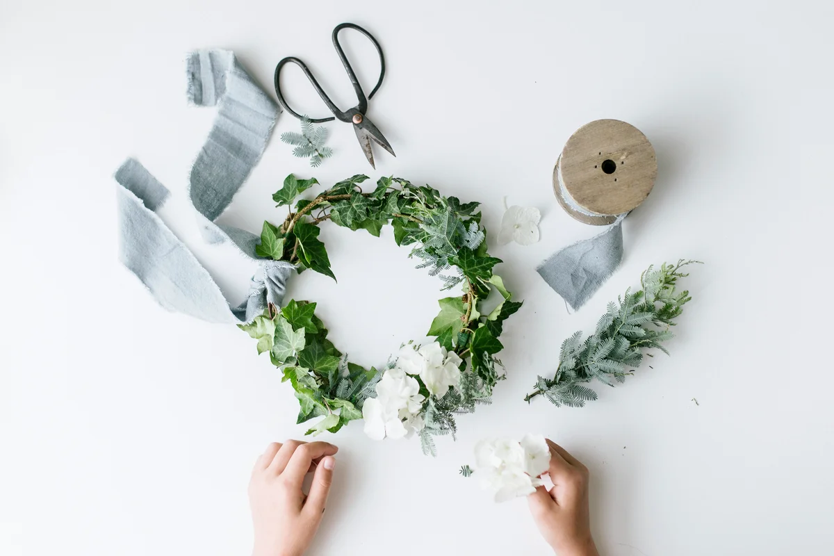 Girl's hands making a festive christmas foliage wreath