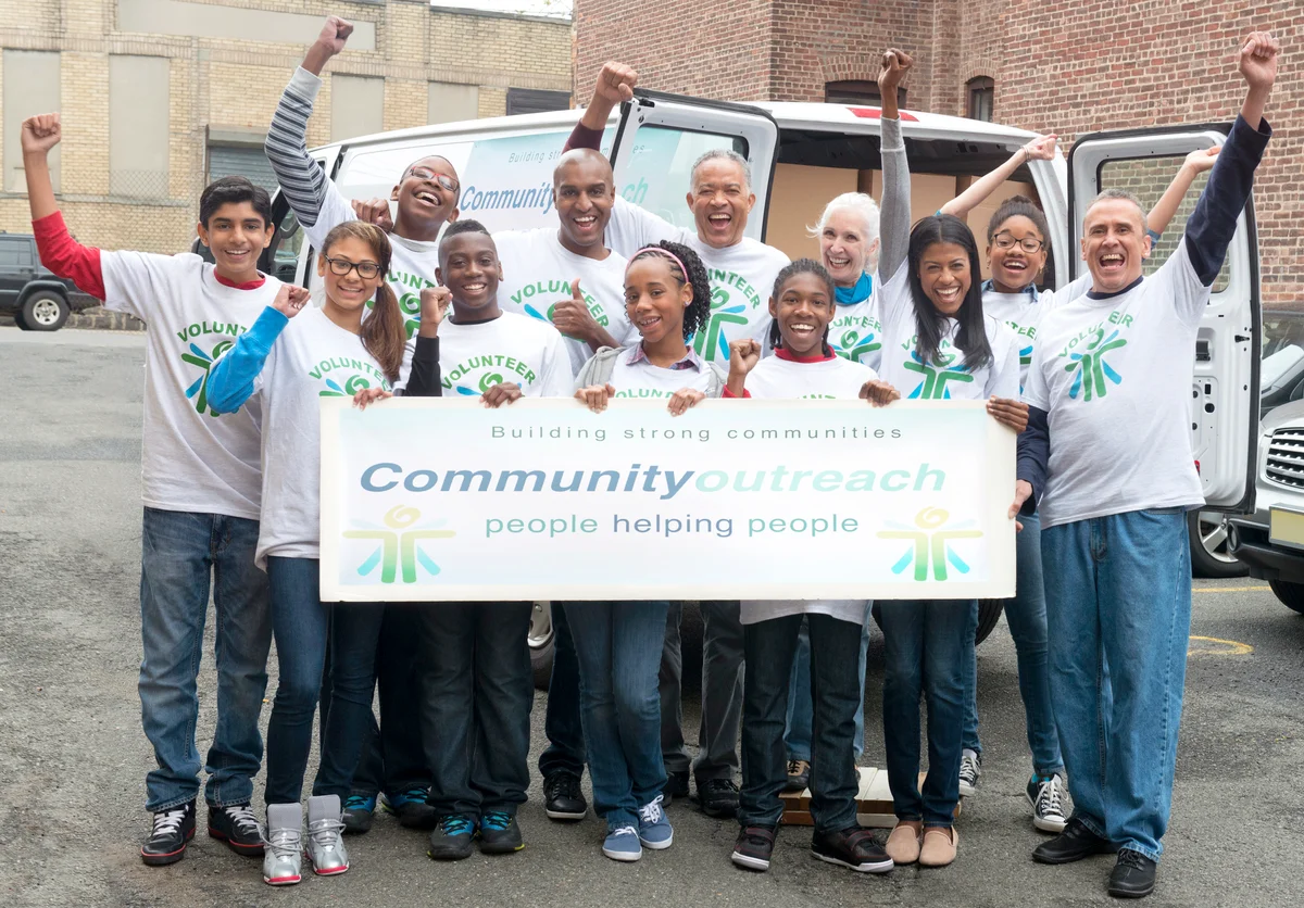 Volunteers holding community outreach banner near delivery van