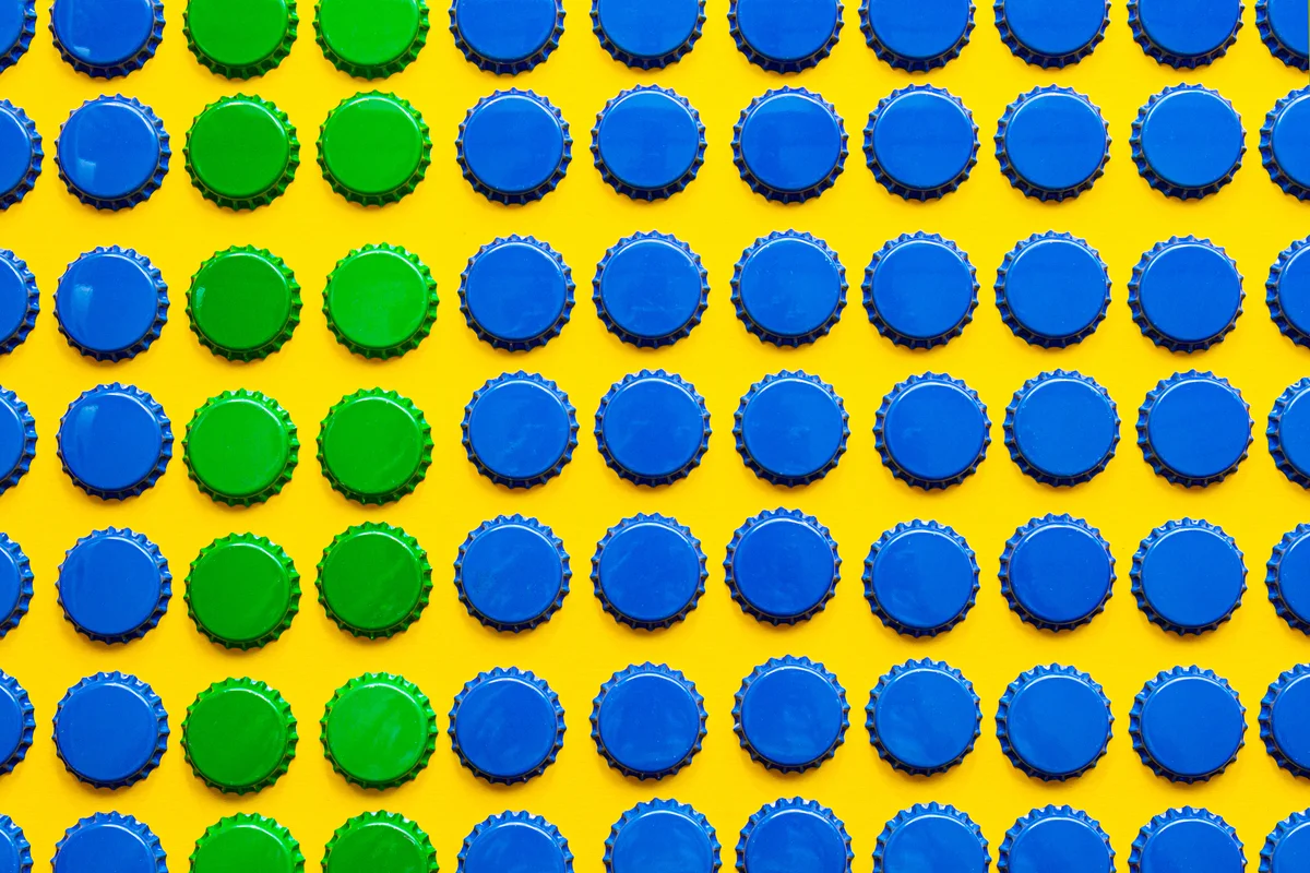 Pattern of many blue and green metal bottle caps on yellow