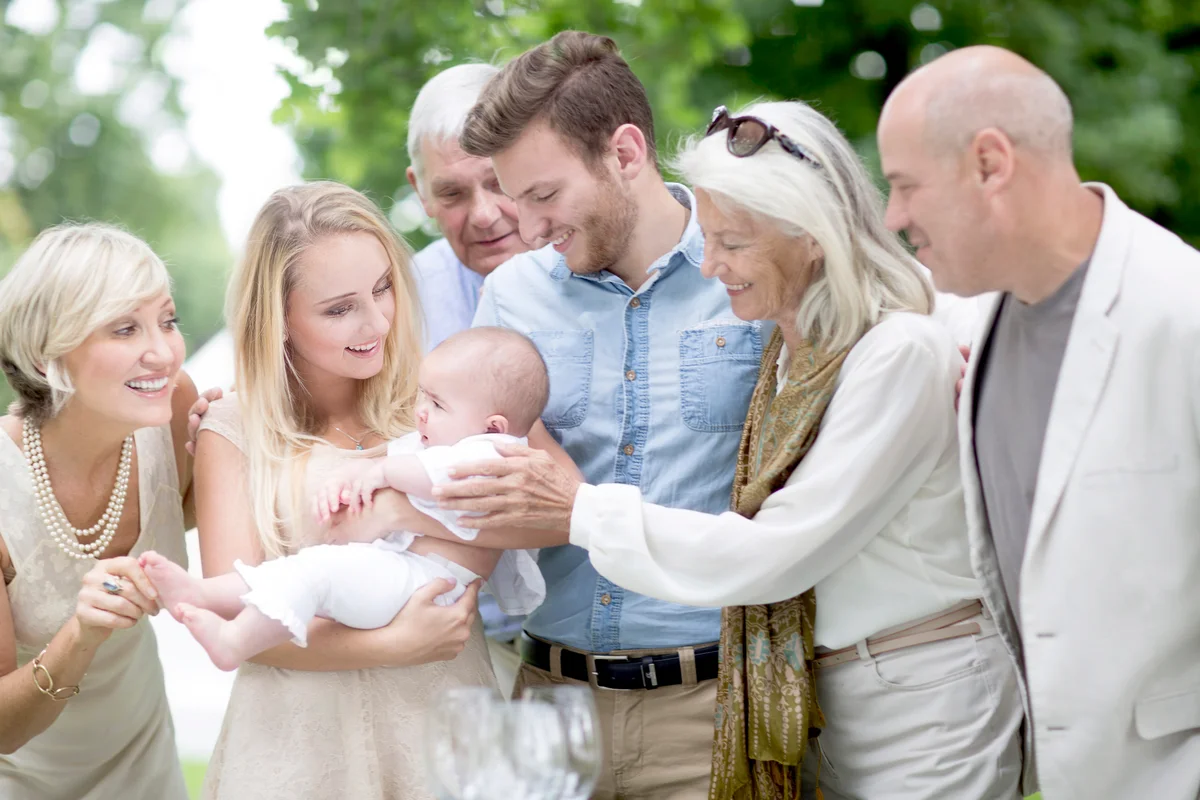 Family gathering around baby outdoors