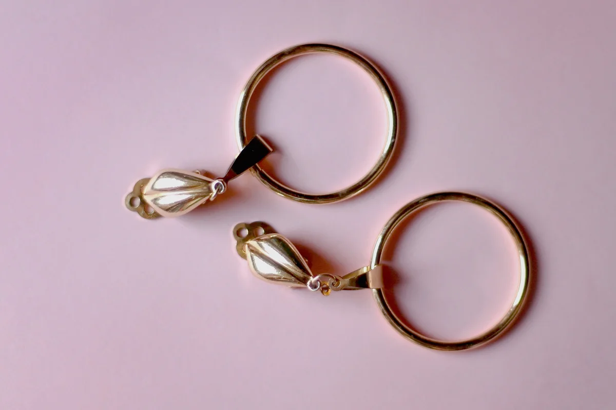 Vintage golden clip-on earrings on pink background