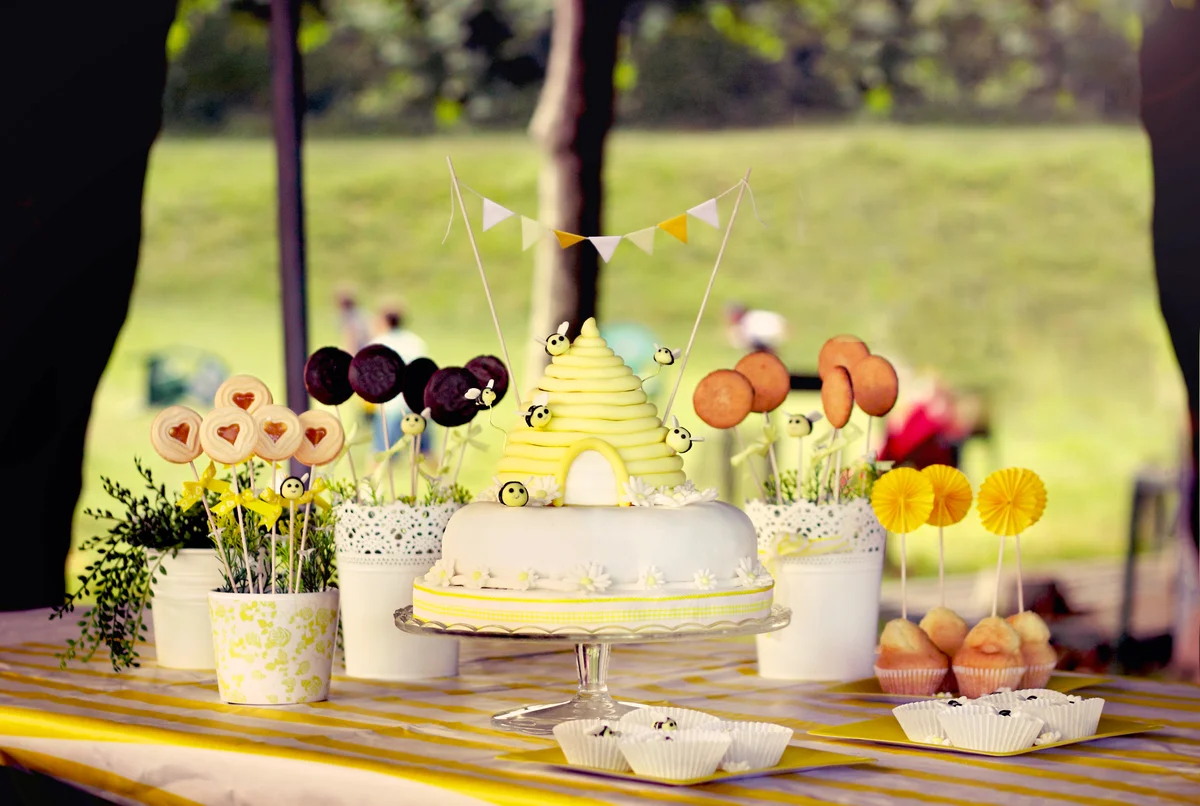 Cake shaped as a honeycomb with fondant bees flying and yellow cute little flags