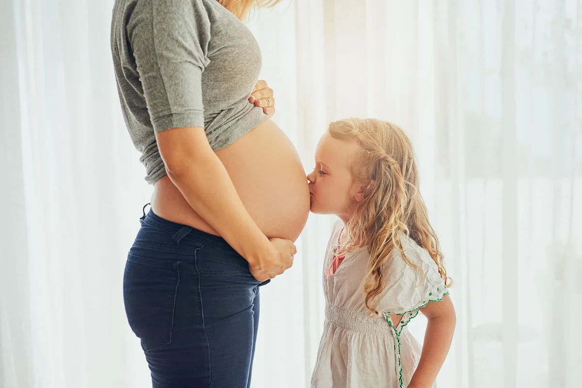 Cropped shot of a little girl kiss her mother's pregnant belly