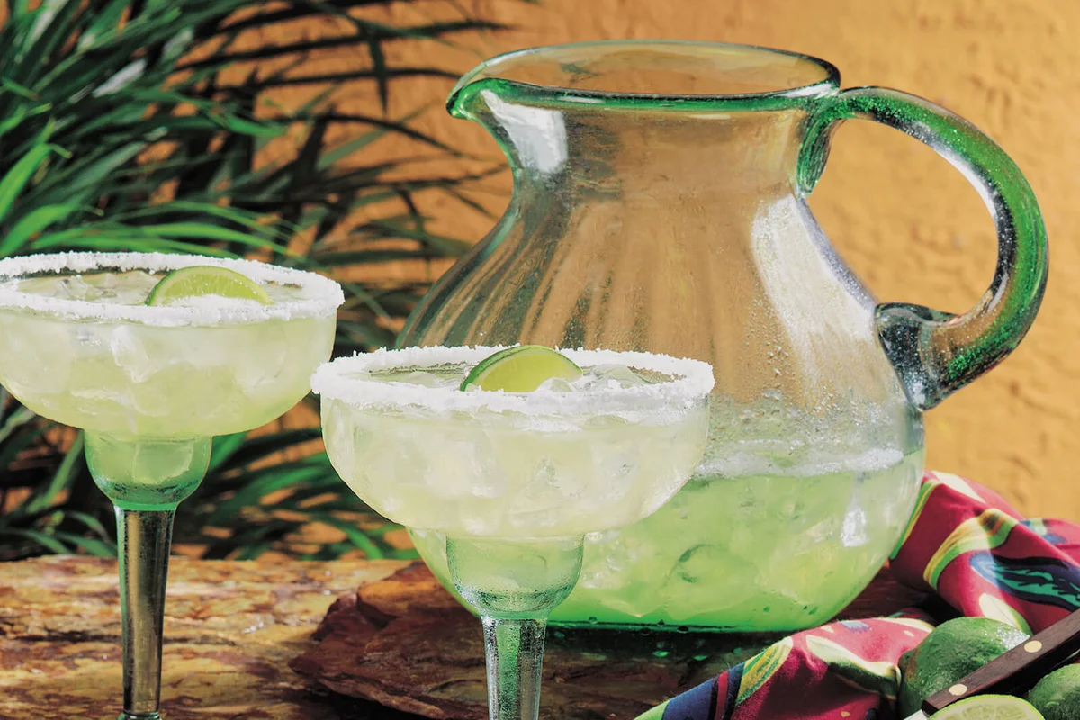 2 margarita glasses with a pitcher of margaritas
