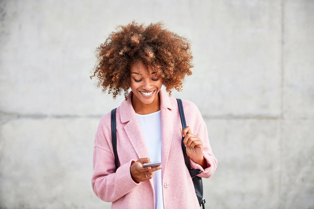 Happy woman text messaging through mobile phone