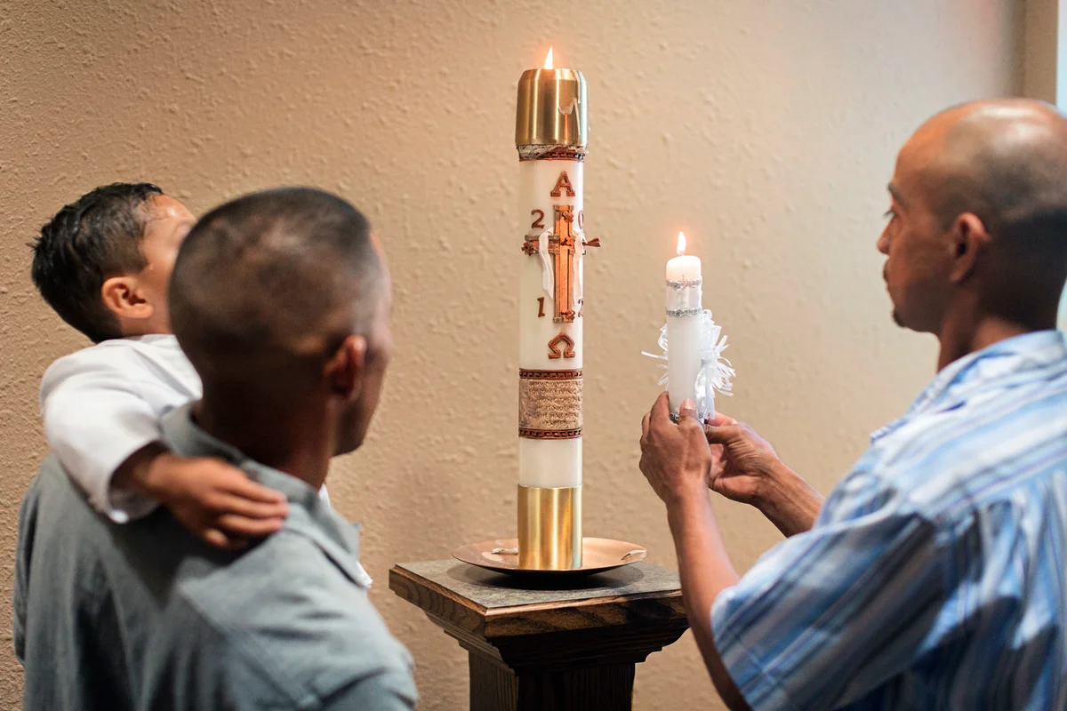 Men lighting baptismal candle in church