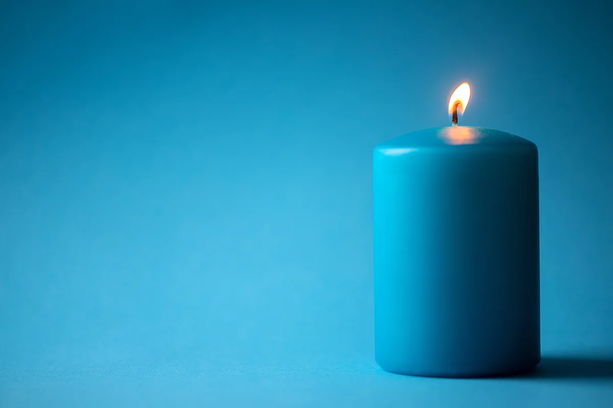 Illuminated Candle Against Blue Background