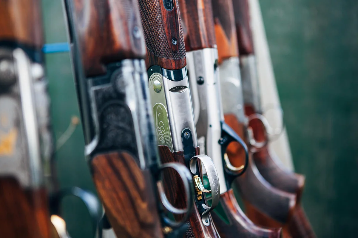 Various styles and types of sporting shotguns standing in a rack