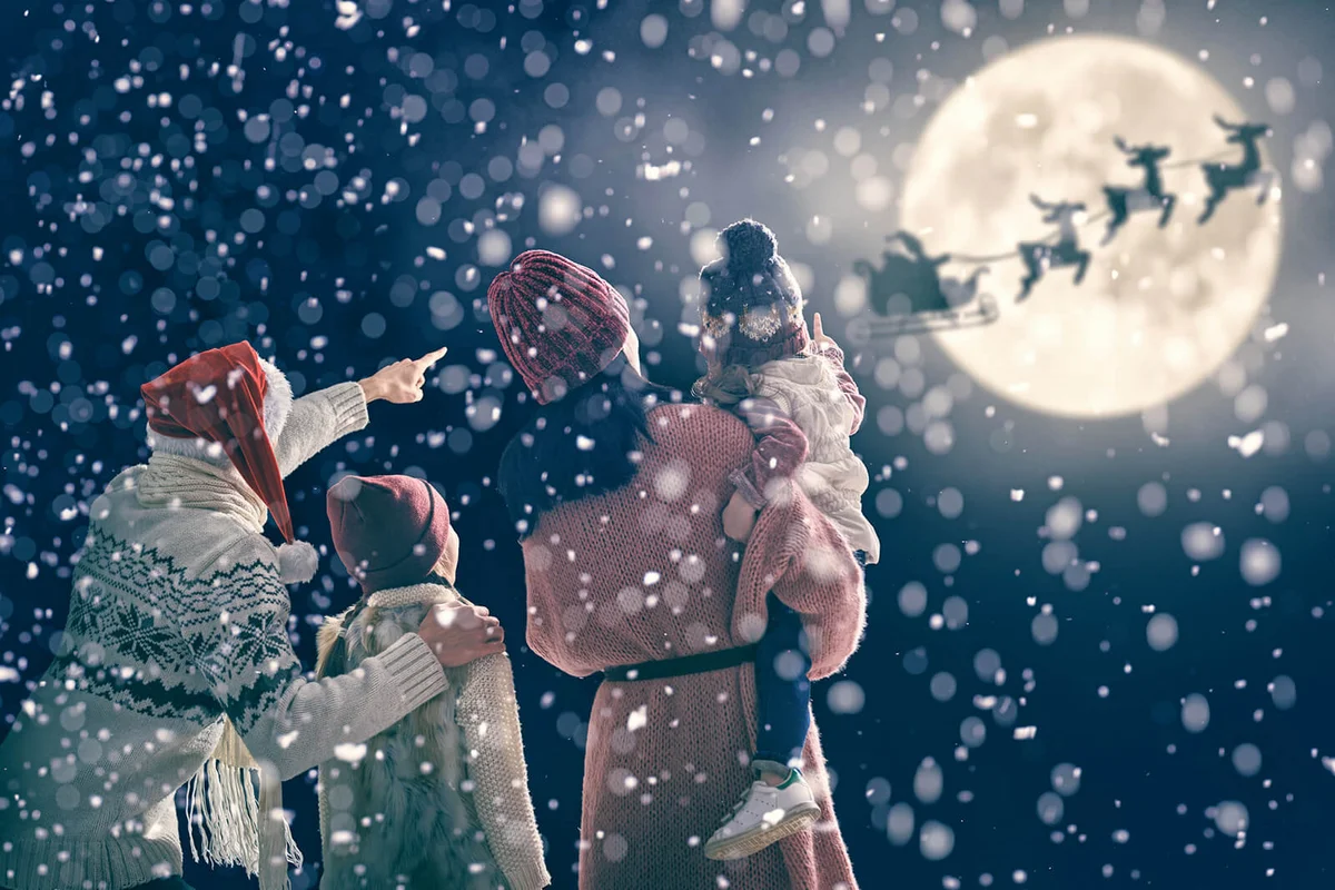 Santa Claus flying in his sleigh against moon sky