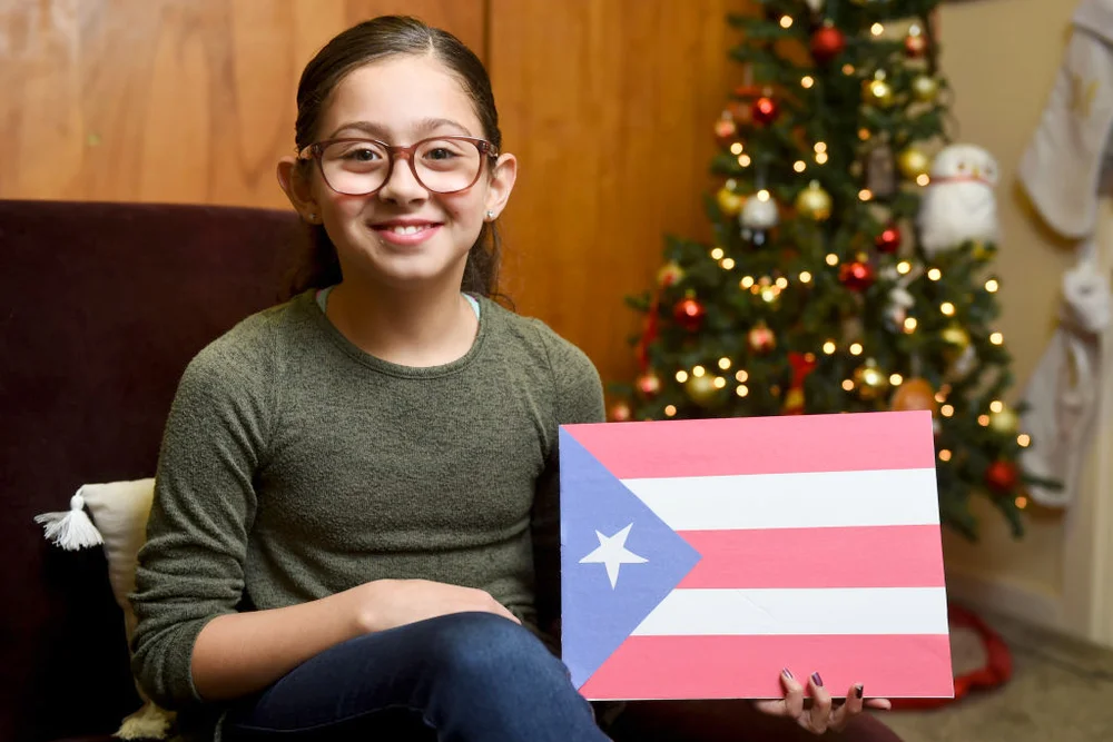 Girl holds a Puerto Rican flag with Christmas tree