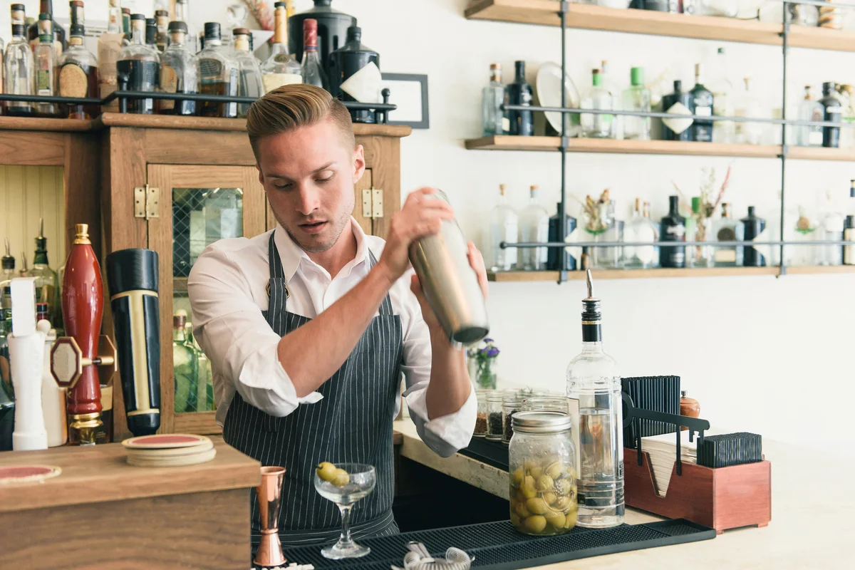 Bartender shaking cocktail shaker in cocktail bar