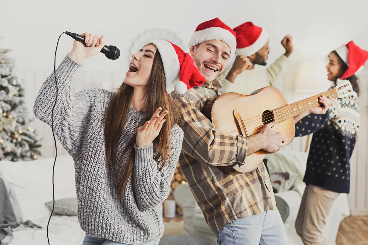 Happy friends singing together and playing on guitar