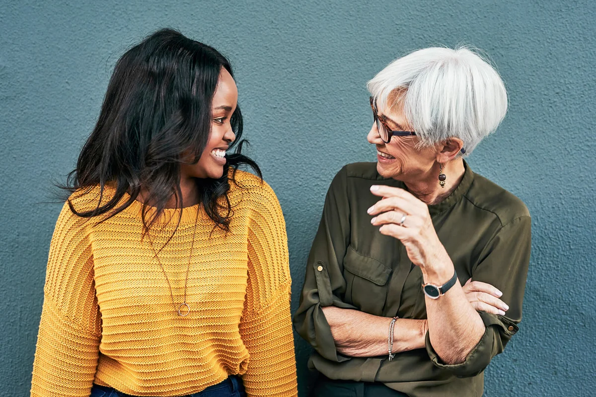 women having a discussion while standing against a wall outdoors