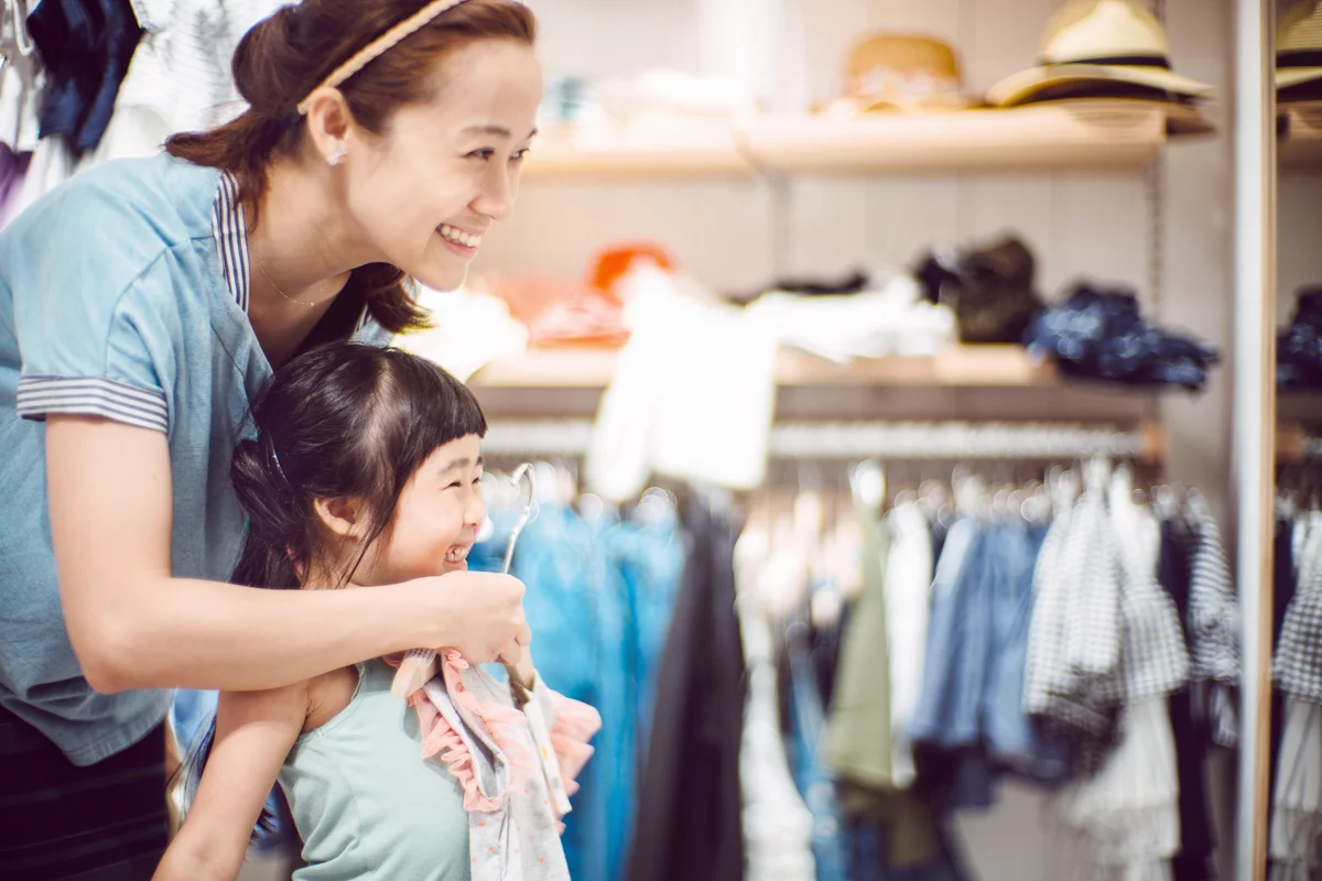 Pretty young mom trying on clothes with her lovely little daughter