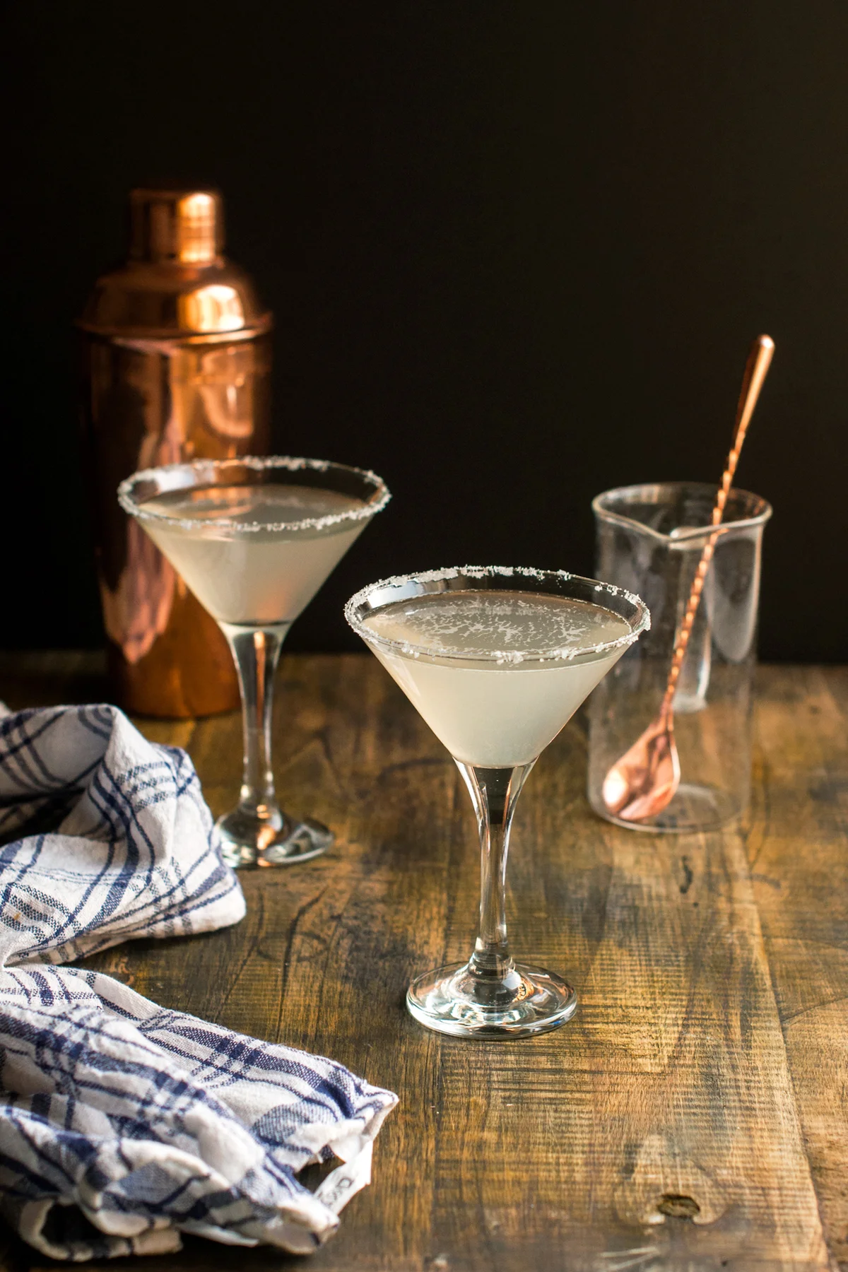 Cocktail in Martini glass with stirrer and copper cocktail shaker