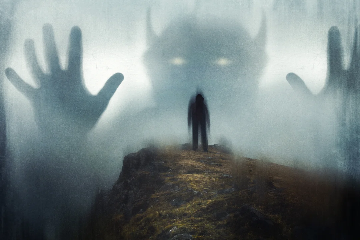 Man looking up at a huge ghostly horned demon appearing out the mist