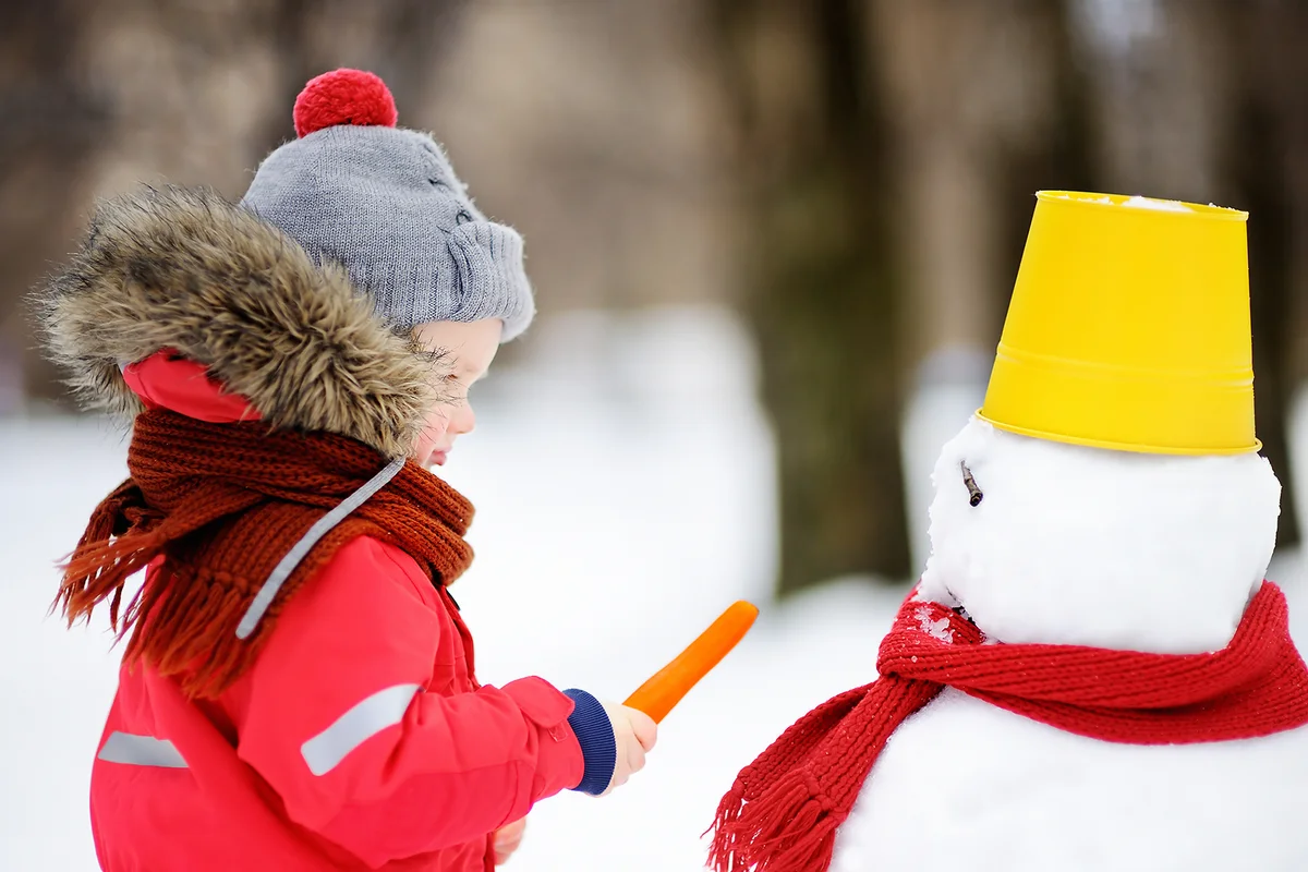 Little boy having fun with snowman.