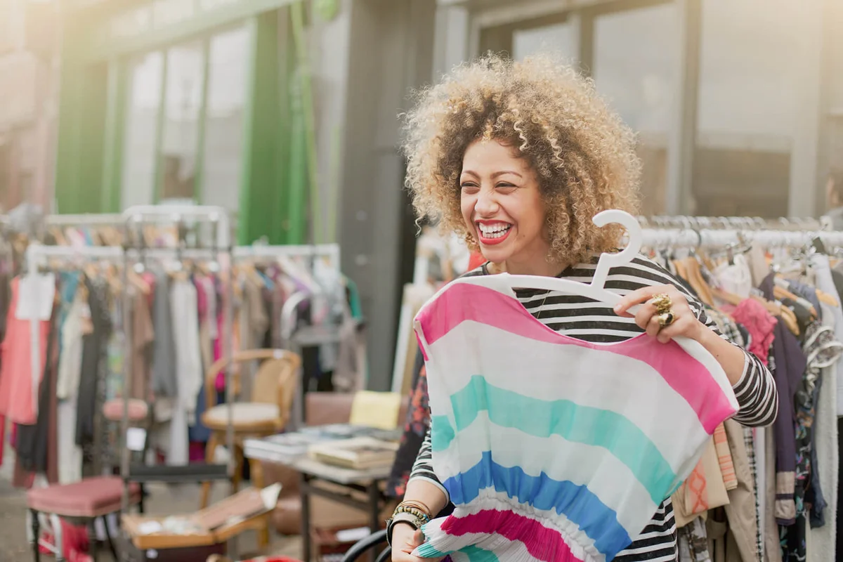 Woman laughing while trying on clothes at market