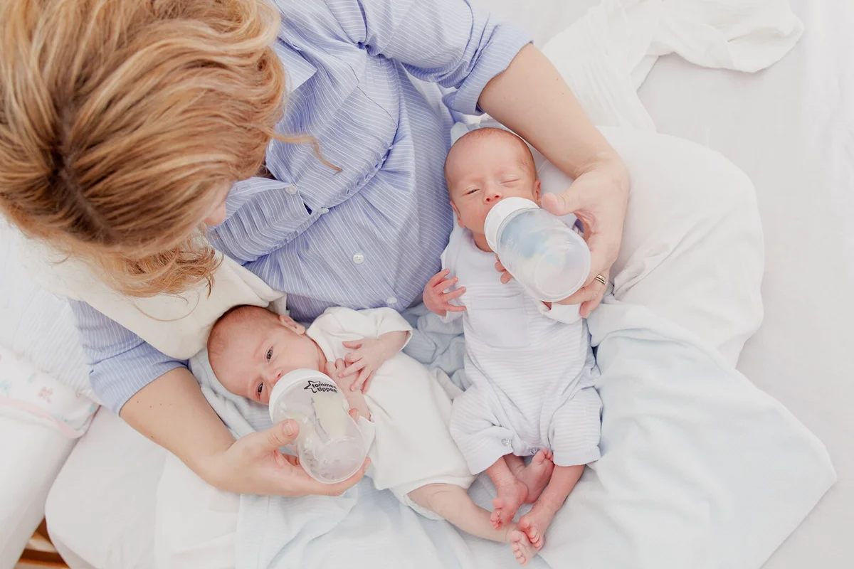 Mother feeding two week old fraternal twins